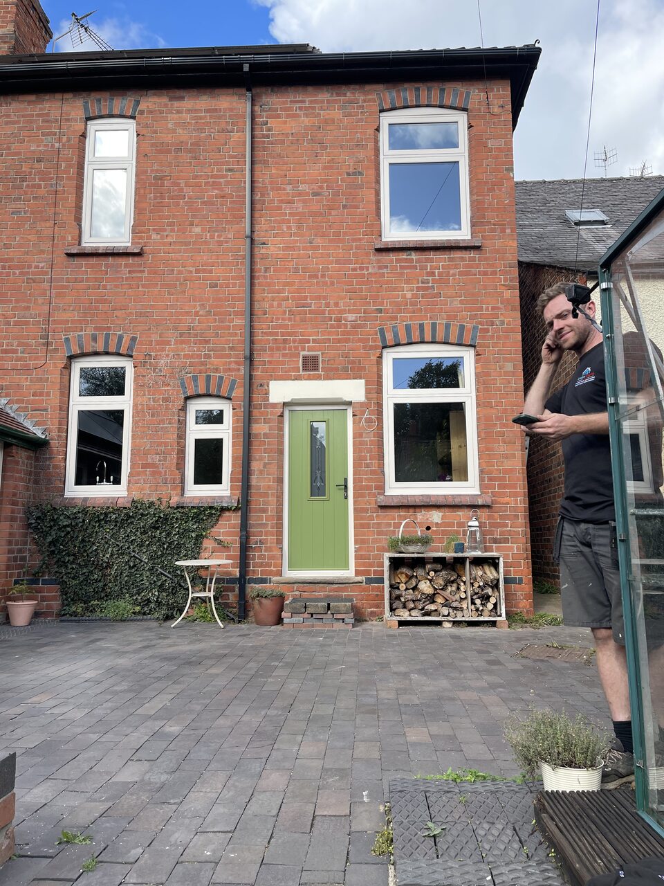 Five white-framed windows and green door on a brick house