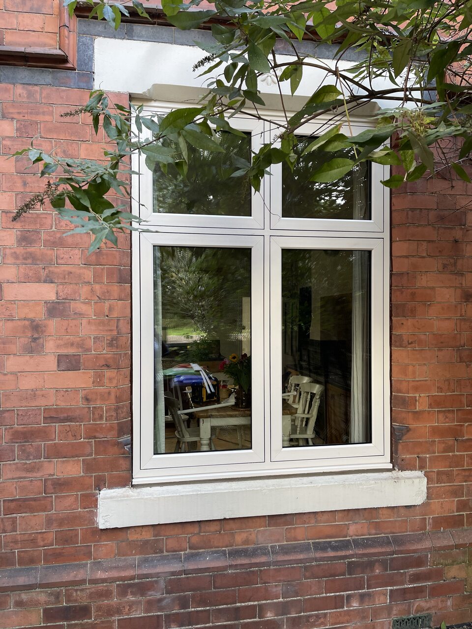White four-pane window fitted in a brick wall
